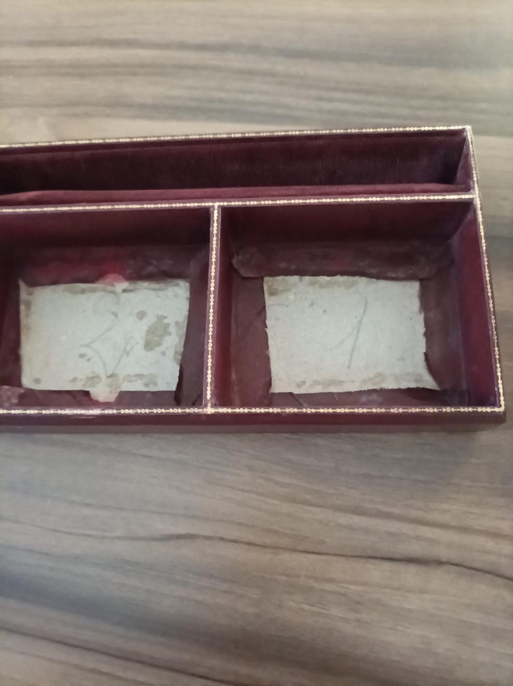 Intérieur d'un coffret à bijoux ancien abîmé : velours mangé, cartons de structure à nu et taches de moisissure